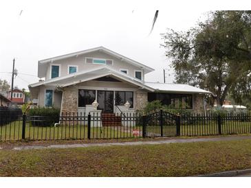 Two-story house with a metal roof, stone accents, and a fenced yard at 306 Avenue C Ne, Winter Haven, FL 33881