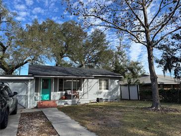 Gray house with teal door, covered porch, and a spacious yard under a bright sky at 308 Kerneywood St, Lakeland, FL 33803