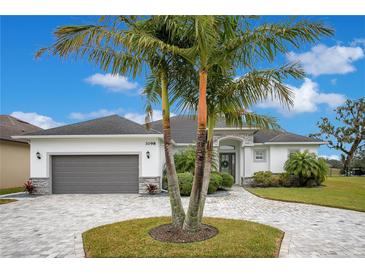 Single-story home with gray garage door, paver driveway, and lush landscaping at 3098 Pearly Dr, Lakeland, FL 33812