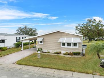 Tan single-wide manufactured home with carport and landscaped lawn at 3221 Pebble Bend Dr, Lakeland, FL 33810