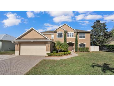 Two-story house with beige exterior, landscaping, and a three-car garage at 4512 Brookshire Pl, Lake Wales, FL 33898