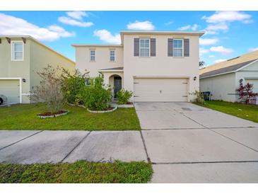 Two-story house with beige exterior, gray door, and attached garage at 5557 Oro Valley Rd, Auburndale, FL 33823