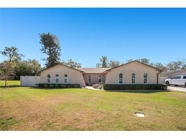 Stunning single-story home featuring arched windows, manicured landscaping, and a sprawling green lawn at 1325 Fairlee St, Lakeland, FL 33813