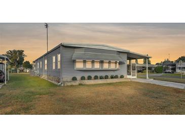 Gray single-wide manufactured home with landscaped lawn and screened porch at 1610 Reynolds Rd # 236, Lakeland, FL 33801