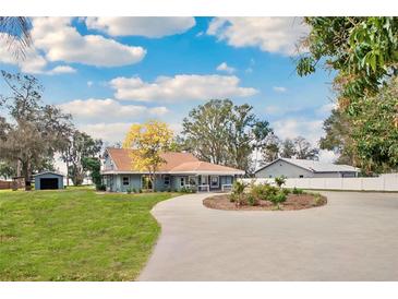 Charming single-story home featuring a circular driveway, well-manicured lawn, and serene landscaping at 20 N Lake Idylwild Dr, Winter Haven, FL 33881