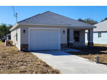 Charming single-story home featuring a two-car garage, gray roof, and neutral stucco exterior at 2013 Alderman Rd, Auburndale, FL 33823