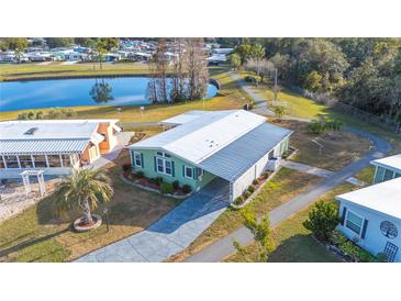 Aerial view of a well maintained, green home with metal roof, landscaping, and pond in the community at 4938 Deerwood Dr, Lakeland, FL 33810