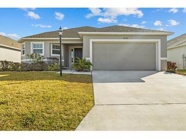 Single-story house with gray siding, two-car garage, and landscaped yard at 6046 Eagle Pointe Dr, Lakeland, FL 33812