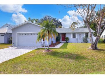 Updated one-story home features a gray exterior, red door, and a well-manicured lawn at 813 Heron Pl, Winter Haven, FL 33884