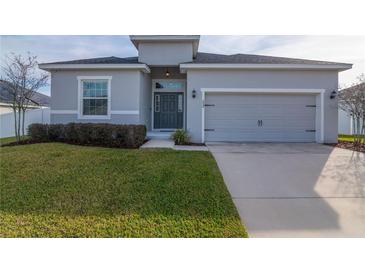 Gray house with two-car garage, landscaping, and a well-maintained lawn at 252 Walkers Point Dr, Auburndale, FL 33823