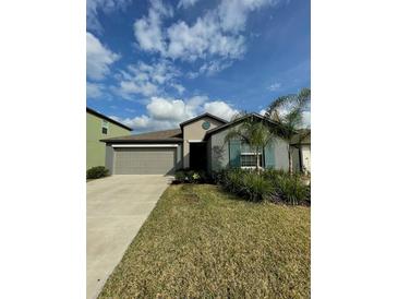 Gray house with teal shutters, two-car garage, and well-maintained lawn at 2591 Red Egret Dr, Bartow, FL 33830