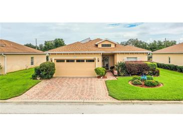 Single-story house with a tan exterior, two-car garage, and landscaped yard at 4128 Aberdeen Ln, Lake Wales, FL 33859