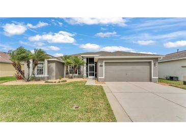 Charming home featuring a two-car garage, manicured lawn, and elegant landscaping with attractive palm trees at 4145 Whistlewood Cir, Lakeland, FL 33811