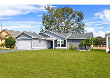 Gray house with white garage door and green lawn at 6235 Egret Dr, Lakeland, FL 33809
