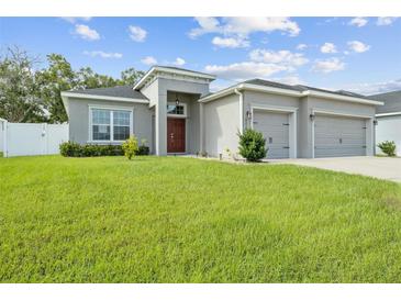 Gray house with two-car garage, lush lawn and red door at 8218 Wilder Loop, Lakeland, FL 33809