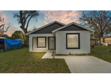 Charming single-story home with white stucco and black trim, featuring a well-maintained front lawn and a modern design at 105 3Rd Eloise St, Winter Haven, FL 33880