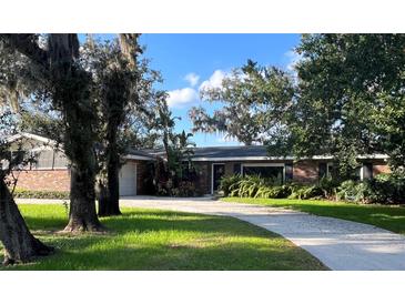 Charming brick home featuring a well-manicured lawn, mature trees and a spacious driveway at 528 Laurel Ln, Lakeland, FL 33813