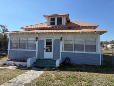 Charming two-story home with blue and cream siding, metal roof, and a welcoming front entrance at 118 S 5Th St, Haines City, FL 33844