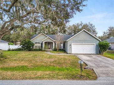 Charming single-story home features a well-manicured lawn, mature trees, and an attached two-car garage at 5942 White Tail Loop, Lakeland, FL 33811