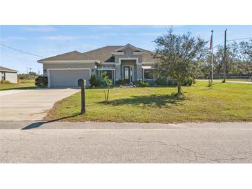 Charming single-story home featuring a well-manicured front lawn and a two-car garage at 824 Ulmer Rd, Frostproof, FL 33843