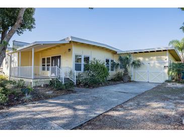 Inviting single-story yellow home with a covered porch, attached garage, and concrete driveway at 827 Sherwood Dr, Lake Wales, FL 33898