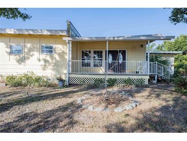 Charming yellow single-story home featuring a covered front porch with white railings and double front doors at 827 Sherwood Dr, Lake Wales, FL 33898