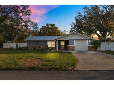 Charming single-story home featuring a metal roof, stone accents, and a well-manicured lawn at 2330 Creek Side Dr, Lakeland, FL 33811