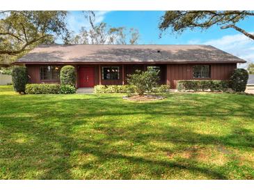 Charming single-story home with a well-maintained lawn and mature landscaping, and red front door at 4613 Little Grove Ln, Lakeland, FL 33813