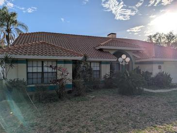 Charming single-story home with a terracotta tile roof and mature landscaping at 838 Lakeshore Dr, Polk City, FL 33868