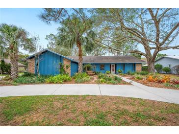 Charming single Gathering home with a long drive and a front yard featuring mature landscaping and a vibrant blue facade at 15 Tera Ln, Winter Haven, FL 33880