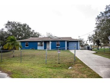 Charming single-story home with blue exterior, spacious front yard and a long driveway leading to an attached garage at 304 Olmo Ct, Winter Haven, FL 33880