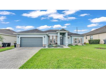 Charming single-story home featuring stone accents, a well-manicured lawn, and a gray two-car garage at 3224 Pearly Dr, Lakeland, FL 33812