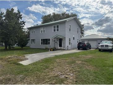 Charming two-story home featuring a driveway leading to a detached garage and a well-maintained lawn at 117 Tremont Dr, Winter Haven, FL 33884