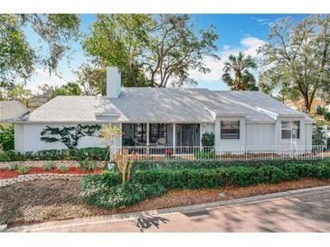 Charming single-story home with a manicured lawn, white picket fence, and inviting front porch at 21 Townhill Dr, Eustis, FL 32726