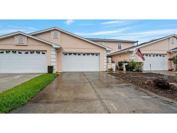 Charming townhome featuring a two-car garage, light pink exterior, and well-manicured lawn at 42 Enclave Dr, Winter Haven, FL 33884