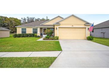 Inviting single-story home featuring a manicured lawn, a two-car garage, and charming landscaping at 1888 Creeks Vista Blvd, Lakeland, FL 33810