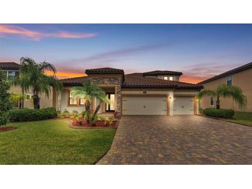 Beautiful home with a paver driveway, three-car garage, and lush landscaping at 3965 Aquilla Dr, Lakeland, FL 33810