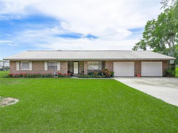 Charming brick home with well-maintained lawn, flower beds, and a three-car garage at 1310 Parker Rd, Lakeland, FL 33811