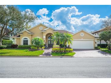 Charming tan single-story home featuring a lush green lawn, mature landscaping, and a welcoming front entrance at 2900 Grasslands Dr, Lakeland, FL 33803