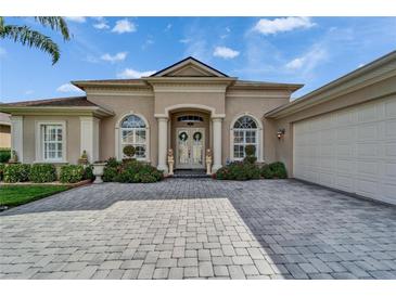 Charming home featuring stucco facade, arched windows, double door entry, manicured landscaping, and brick paver driveway at 565 Osprey Landing Dr, Lakeland, FL 33813