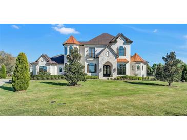 A beautiful two-story home with a large lawn, attractive shrubbery, and stone accents, under a picturesque partly cloudy sky at 5676 Case Ln, Lakeland, FL 33813
