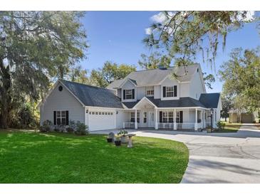 Charming two-story traditional home featuring a covered porch, garage, and lush green lawn at 6810 Crystal Beach Rd, Winter Haven, FL 33880