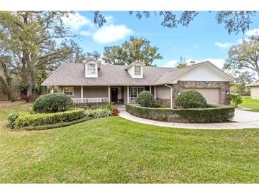 Charming single-story home featuring manicured landscaping, stone accents, dormer windows, and a welcoming front porch at 7010 Parliament Pl, Lakeland, FL 33809