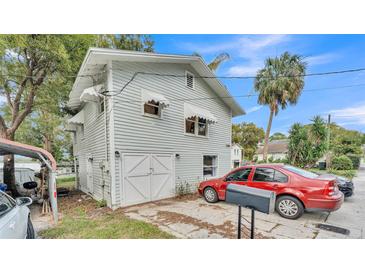 Charming home featuring a two-car garage, red sedan, and tasteful awnings over the upstairs windows at 723 W Patterson St, Lakeland, FL 33803