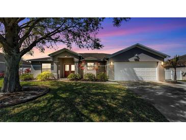 Charming single-story home with a well-manicured lawn, mature trees, and a two-car garage at 8158 Woodvine Cir, Lakeland, FL 33810