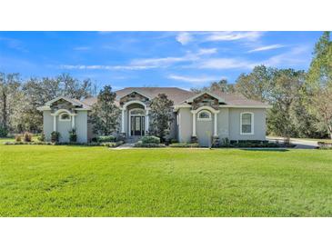 Charming single-story home featuring stone accents and a meticulously manicured front yard with a vibrant green lawn at 9216 Tom Moore Rd, Lakeland, FL 33810