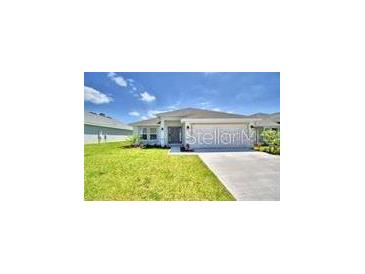 Charming single-story home with a well-manicured lawn and a long driveway leading to an attached garage at 1588 Leamington Ln, Winter Haven, FL 33884