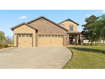 Charming home featuring a stone facade and a three-car garage, complemented by a well-maintained lawn at 2210 Moraine Ct, Lakeland, FL 33805