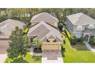 Aerial view of a two-story home with a brick driveway and a well-maintained lawn with mature trees at 4759 Lathloa Loop, Lakeland, FL 33811