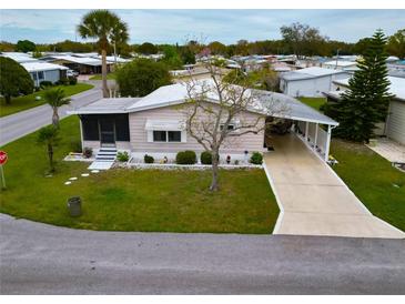 Charming single-story home with a well-manicured lawn, a carport, and a screened in porch at 4985 Deerwood Dr, Lakeland, FL 33810